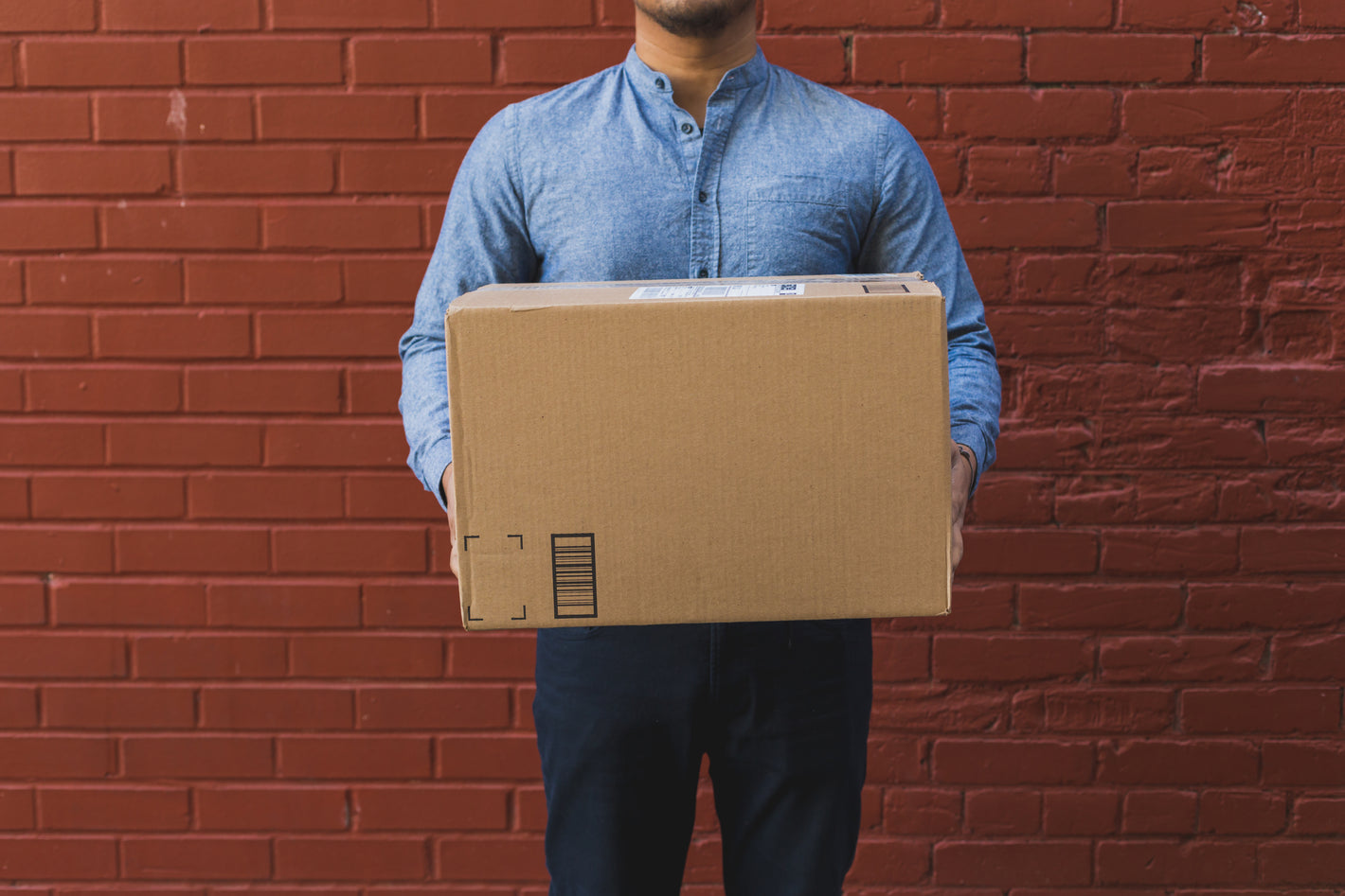 man-holding-shipping-box-on-red-brick - KENJI KOI Products